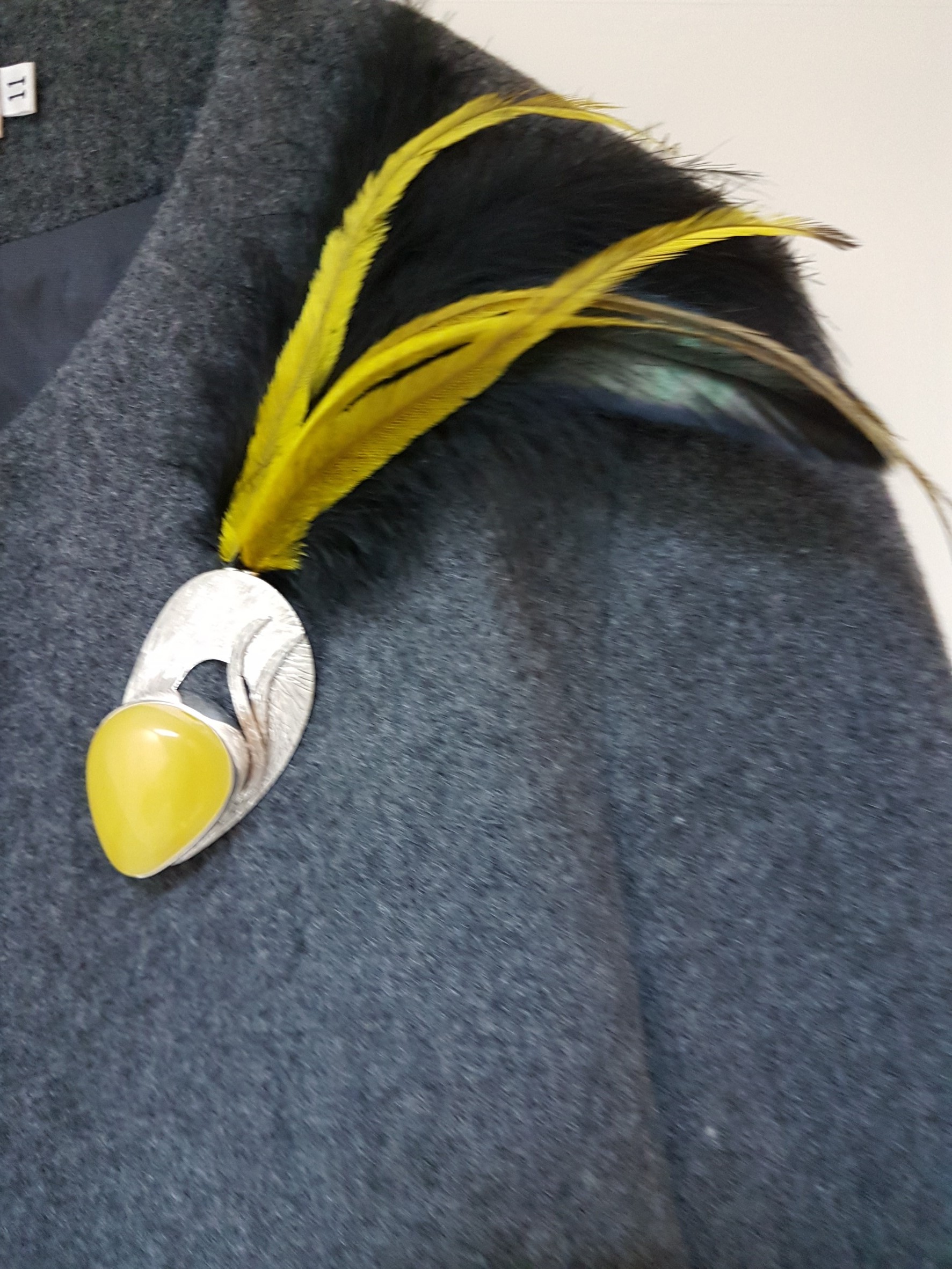 出自波蘭著名的琥珀藝術設計創作人之作品.將精選的琥珀鑲崁與銀飾工藝設計結合並以獨特的黃色及黑色羽毛搭配出獨特的創意飾品-胸針與項鍊二用飾品